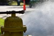 Fire hydrant with wrench on top spraying water into the street
