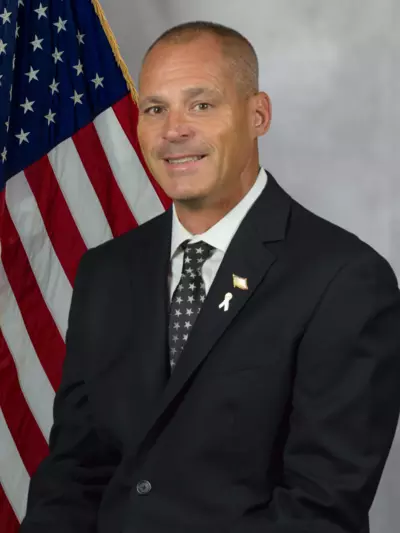picture of Commissioner Mark Caruso in front of an American flag